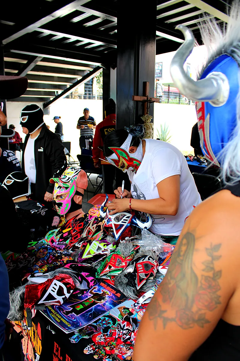 Firma de máscaras de luchadores en una mesa de Expo Máscaras 2026