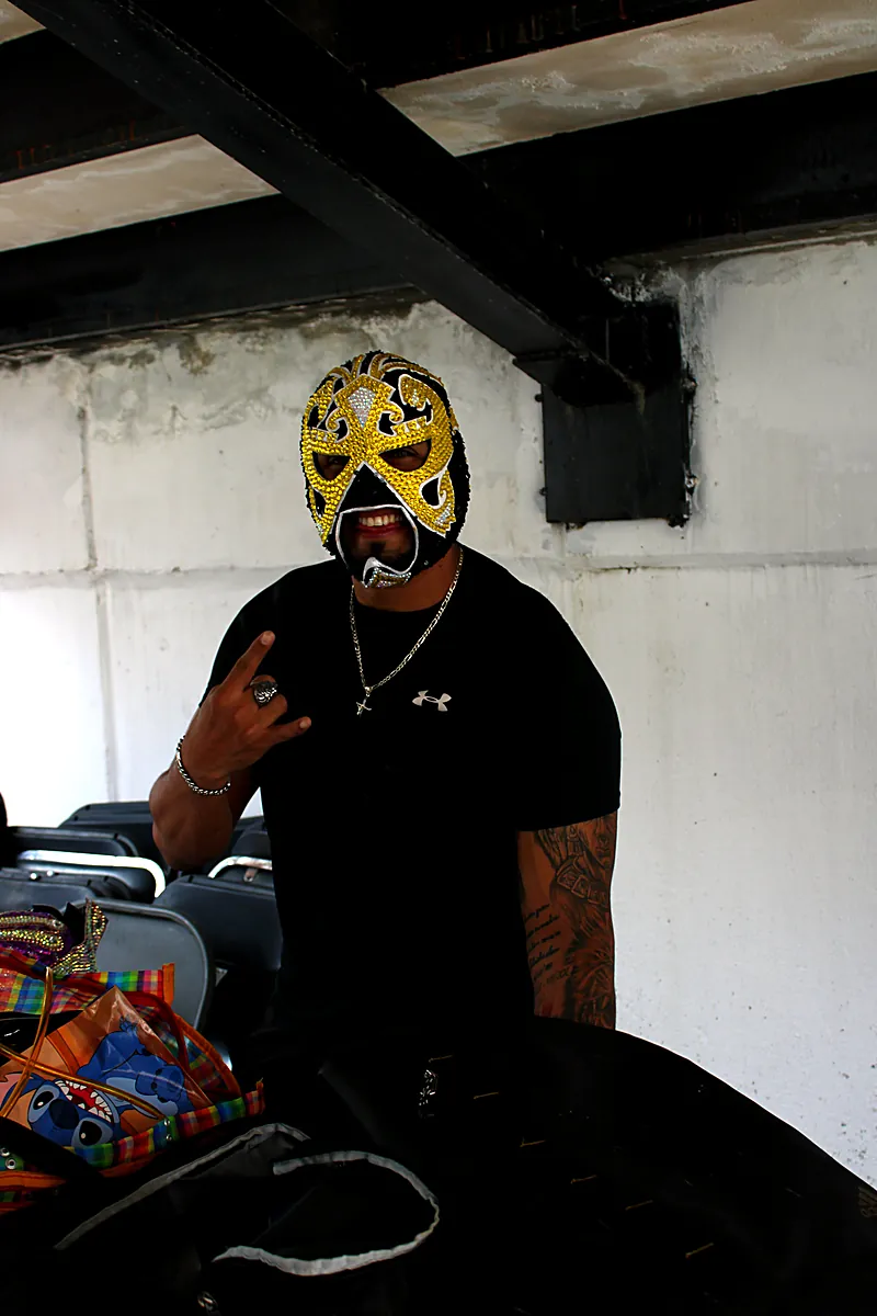 Luchador con máscara dorada haciendo pose de lucha libre en Expo Máscaras