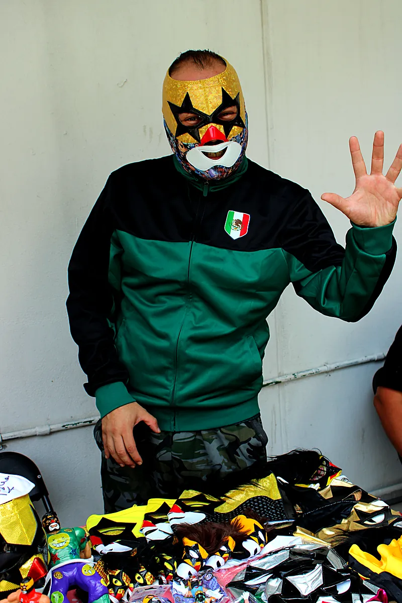 Luchador con máscara dorada saludando al público durante la kermés de Expo Máscaras